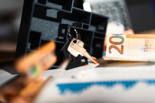 Wohnungsgrundriss mit Schlüsseln und Bargeld zur Finanzplanung beim Wohnen